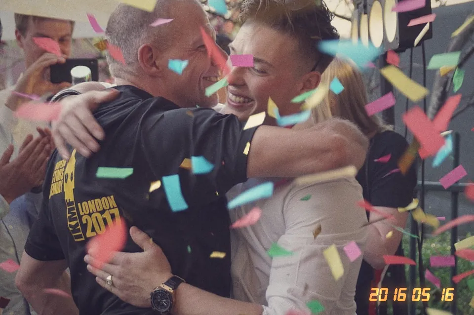 Bij de opening van Kamato Gym omhelzen twee mensen elkaar terwijl er confetti valt.