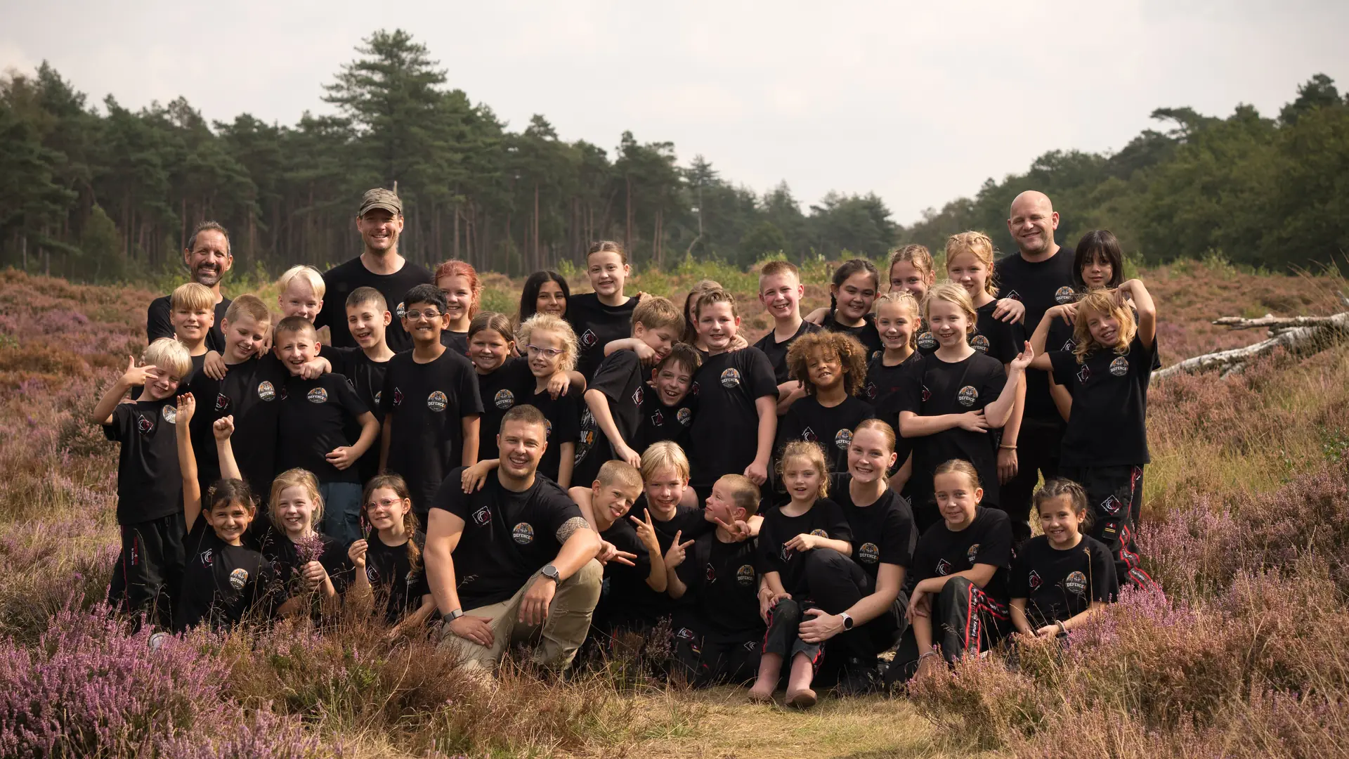 De hele Defence4Kids-groep met hun instructeurs op de heide tijdens het kinderkamp