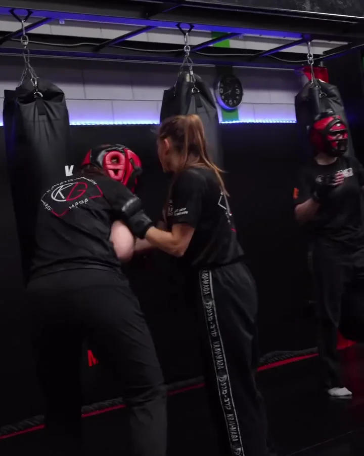 Twee vrouwen met hoofdbescherming oefenen een verdediging tegen elkaar